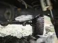 Widok od dołu na terenowy samochód z widocznym przegubem, oponą i kamienistym podłożem.