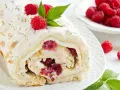 Rolada bezowa z mascarpone i malinami, posypana cukrem pudrem i płatkami migdałów.