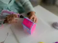 Dziecko tworzy domek z różowego i niebieskiego filamentu. Długopis 3d nie wciąga filamentu, ale tworzy trójwymiarowe dzieło.