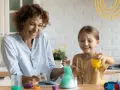 Mama i córka śmieją się, wykonując spektakularne eksperymenty dla dzieci z zieloną pianą w probówce.