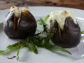 Zwei gefüllte Feigen, die auf einem Teller mit Rucola und Balsamico-Glasur liegen. Ein köstliches Gericht, das zeigt, wie man Feigen grillen kann.