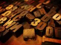 Drewniane czcionki do druku, litery i cyfry, tworzą tło dla numerologii imienia i nazwiska.