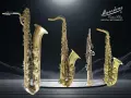 Vier verschiedene **Saxophon Arten** von Mansdone, von groß bis klein, glänzen auf einer Spiegelplattform vor einem dramatischen Hintergrund.