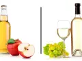 Jabłkowy drink czy białe wino? Po lewej butelka z jabłkowym napojem i jabłka, po prawej kieliszek i butelka białego wina z winogronami.