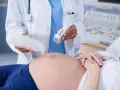 Badania prenatalne w 12 tygodniu ciąży: lekarz aplikuje żel na brzuch pacjentki przed badaniem USG.