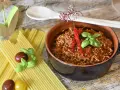 Un invitante ragù, pronto per la pasta, con peperoncini e basilico. La ricetta perfetta per un pranzo gustoso.