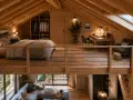 Aménagement mezzanine chaleureux avec lit douillet, bureau et coin détente. L'espace maximise le bois et la lumière naturelle.