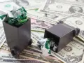 Dwa małe kosze na śmieci wypełnione pogniecionymi papierkami leżą na stosie banknotów dolarowych. Symbolizuje to opłatę za śmieci w miejscu zamieszkania czy zameldowania.