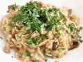 Kremowe risotto z grzybami, posypane świeżą natką pietruszki, wygląda apetycznie.