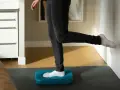 Personne effectuant des exercices de renforcement de la cheville sur un step bleu, idéal pour la rééducation après une entorse.
