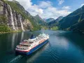Rejs statkiem "Norwegian Fjord Explorer" przez malownicze fiordy Norwegii, z wodospadami i zielonymi zboczami.