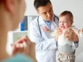 Lekarz uspokaja płaczące dziecko, które przechodzi skok rozwojowy 4 latka. Mama wspiera malucha.