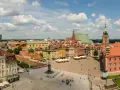 Uroczy city break z Warszawy. Rynek Starego Miasta tętni życiem, z kolorowymi kamieniczkami i Zamkiem Królewskim w tle.