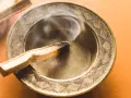 Humo ascendente de un palo santo quemándose en un cuenco metálico. Descubre a qué huele el palo santo.