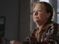 Ewa Żukowska w kolorowym swetrze, zamyślona, patrzy w bok.