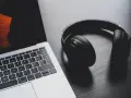 Słuchawki leżą obok laptopa. Może to być sygnał, że występuje brak dźwięku w laptopie i potrzebne są słuchawki do słuchania.