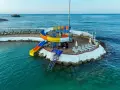 Kolorowe zjeżdżalnie wodne i leżaki na wyspie w Orange County Alanya, nad turkusowym morzem.