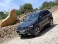 Schwarzer Jeep Grand Cherokee 3.0 CRD 250 PS im Gelände. Ein großer Felsbrocken liegt daneben.