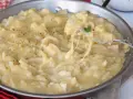 Una padella piena di cremosa pasta con patate, condita con pepe nero. Un piatto confortante e saporito.