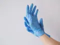 Ręce w niebieskich rękawiczkach nitrylowych, idealnych jako rękawiczki do laboratorium chemicznego.