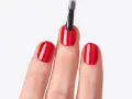 Application d'un top coat sur des ongles rouges brillants. Le top coat, c'est quoi ? C'est la touche finale pour une manucure parfaite.