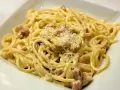 Pyszne spaghetti carbonara z kawałkami guanciale i parmezanem. Idealna śmietana do carbonary to sekret tego dania.