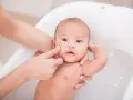 Delikatna kąpiel niemowlaka w wanience. Czy można myć dziecko z gorączką? Tak, ale w letniej wodzie, by pomóc mu się ochłodzić.