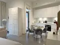 Acogedor cocina salón comedor de 30 m2 con muebles blancos, mesa redonda y sofá.