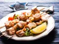 Spiedini di pesce succulenti, con gamberi e salmone grigliato, serviti su un letto di insalata con spicchio di limone.
