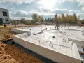 Budowa garażu murowanego: trwa wylewanie fundamentów z betonu i styropianu. Widać zbrojenie i elementy instalacji.