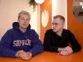 Dwóch mężczyzn siedzi przy pomarańczowym stole. Jeden w niebieskiej bluzie z napisem "SUPREME", drugi w czarnej koszulce. Rozmawiają o kebabie friza.