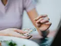 Dłoń trzyma kapsułkę i opakowanie z suplementami. Może to być pikolinian chromu, wspierający zdrowy tryb życia.