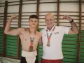 Dwóch zapaśników sumo z medalami, młody zawodnik w tradycyjnym stroju i trener. Prawdopodobnie świętują rekord Polski suma.