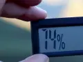 En digital hygrometer visar 74%, vilket indikerar normal luftfuktighet inomhus.