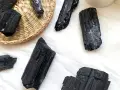 Cristales de turmalina negra, algunos en una cesta de mimbre, listos para atraer el amor y la protección.