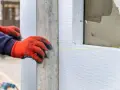 Mani con guanti rossi posano pannelli di polistirene estruso, materiale isolante per l'edilizia.