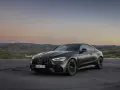 Ciemnoszare coupé Mercedes-AMG CLE 53 na tle górskiego krajobrazu o zachodzie słońca.