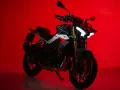 La Benelli TNT 500, con il suo design aggressivo e i fari a LED luminosi, si staglia su uno sfondo rosso acceso, pronta a conquistare la strada.