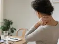 Donna con mal di testa che si massaggia il collo, suggerimenti su come far passare il mal di testa.