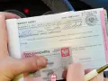 Dłoń trzyma mandat karny i dowód osobisty.