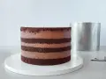 Czekoladowy tort bomba z kremem, gotowy do dekoracji. Obok metalowa obręcz.