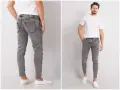 Szare jeansy męskie z przetarciami, dopasowane, z białym t-shirtem i białymi slip-onami.