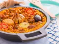 Arroz al horno valenciano con garbanzos, tomate, patata, ajo y morcilla en una paellera.