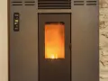 Stufa a pellet con fiamma viva visibile. Il pannello di controllo mostra "19.5°". La distanza candeletta stufa pellet è ottimale per l'accensione.