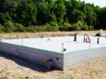 Betonowe fundamenty pod dom parterowy z instalacją hydrauliczną. Zielona izolacja na obrzeżach płyty.