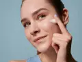 Donna applica schiuma sul viso, un gesto essenziale per la skincare routine mattina e sera. Pelle luminosa e curata.