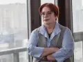 Kobieta w okularach, z rudymi włosami, opiera się o okno. Jej postawa sugeruje siłę i determinację w odpowiedzi na pytanie, jak żyć po rozwodzie.