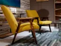 Due poltrone gialle con struttura in legno scuro, un tappeto patchwork e un tavolino in vetro. Un tocco di arredamento anni '70 italiano.