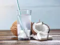 Verre d'eau de coco fraîche avec des morceaux de noix de coco. Une boisson naturelle pour soulager la constipation.