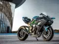 Kawasaki H2R – maszyna, która w mgnieniu oka osiąga 100 km/h. Czarny, sportowy motocykl z zielonymi akcentami na ramie, zaparkowany przed nowoczesnym budynkiem.